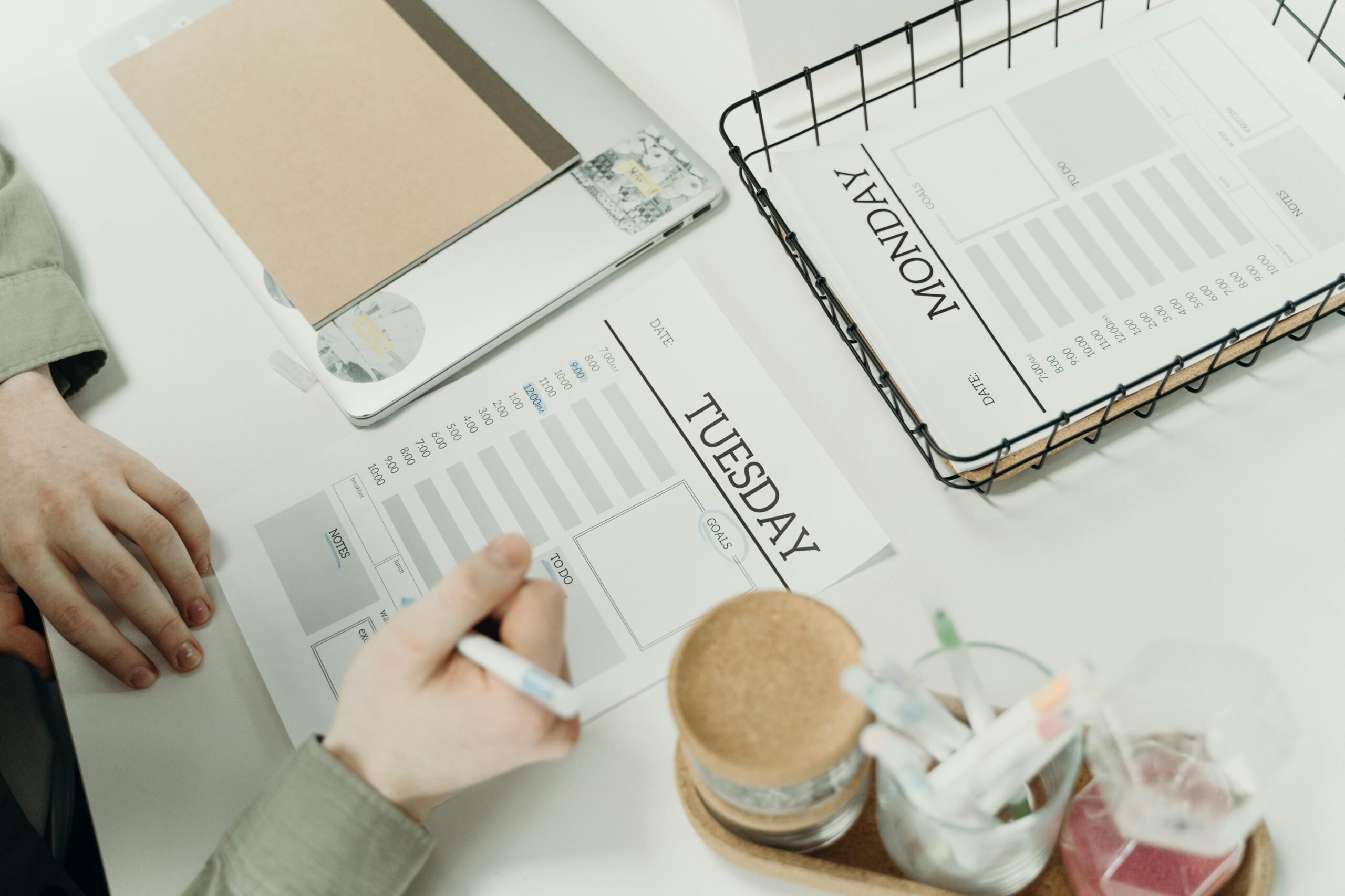A professional organizing the week with detailed schedule planners in an office setting.